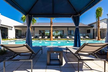 a swimming pool with two lounge chairs and a table
